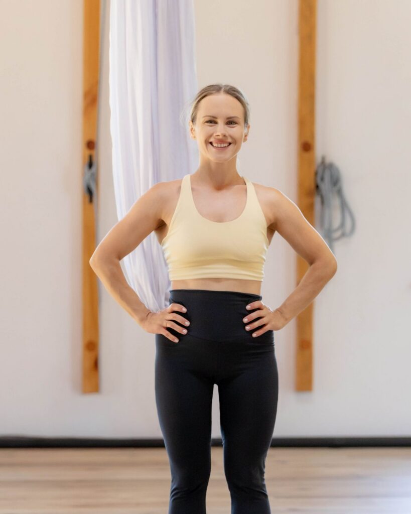 Klaudia Hennig smiling aerial yoga and sling instructor standing next to a white hammock