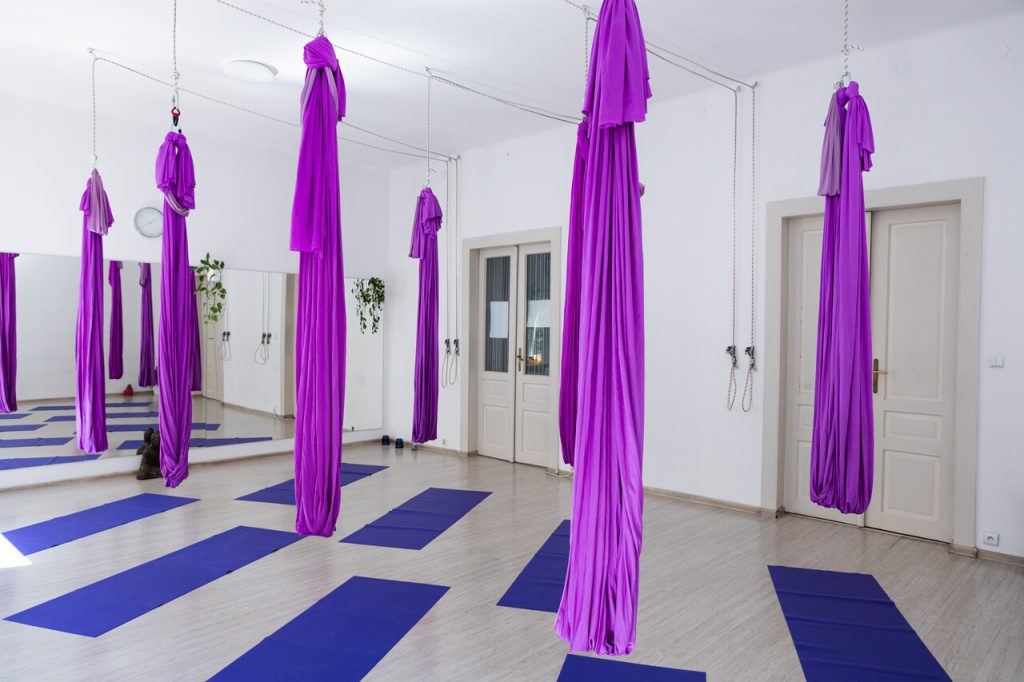 Jasna sala do aerial yogi z fioletowymi hamakami w Akademii Meli Melo w Krakowie